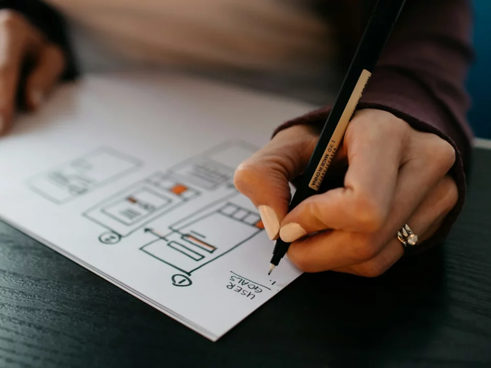 Une personne dessine des wireframes sur une feuille de papier